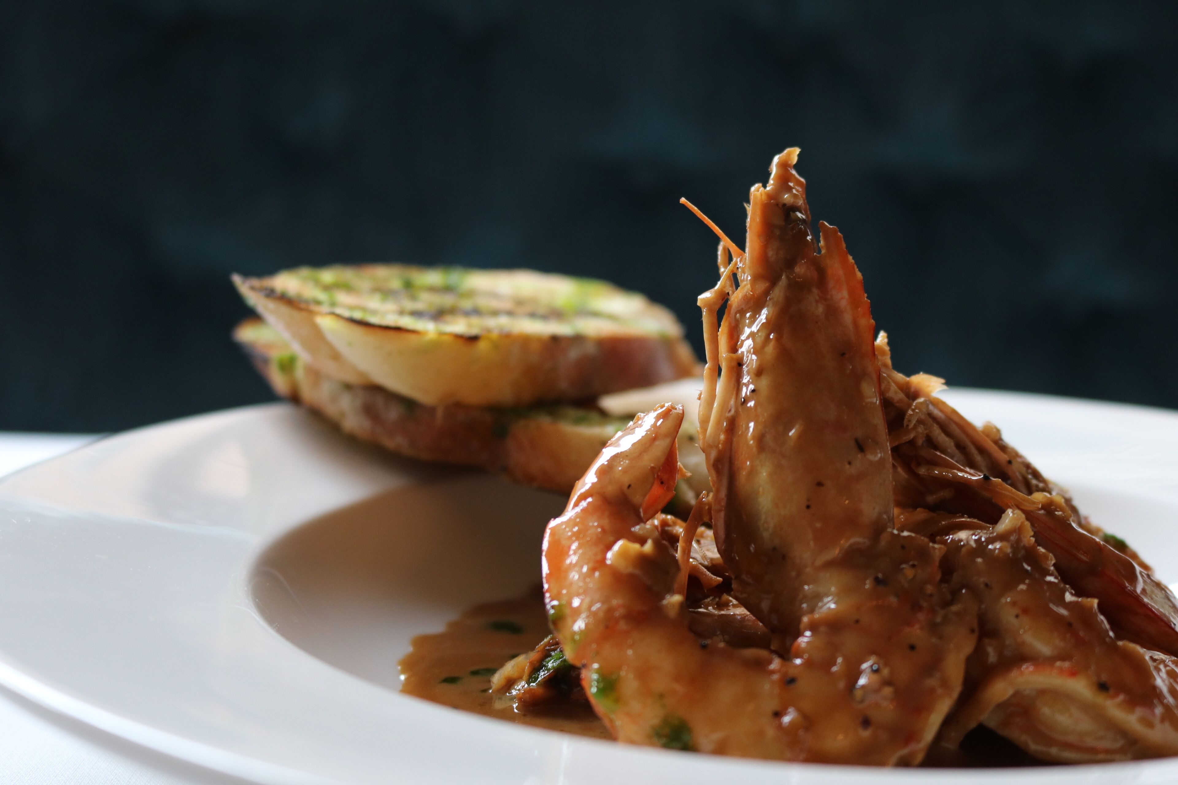 A plate with a seafood dish, possibly lobster, and a slice of toasted bread.