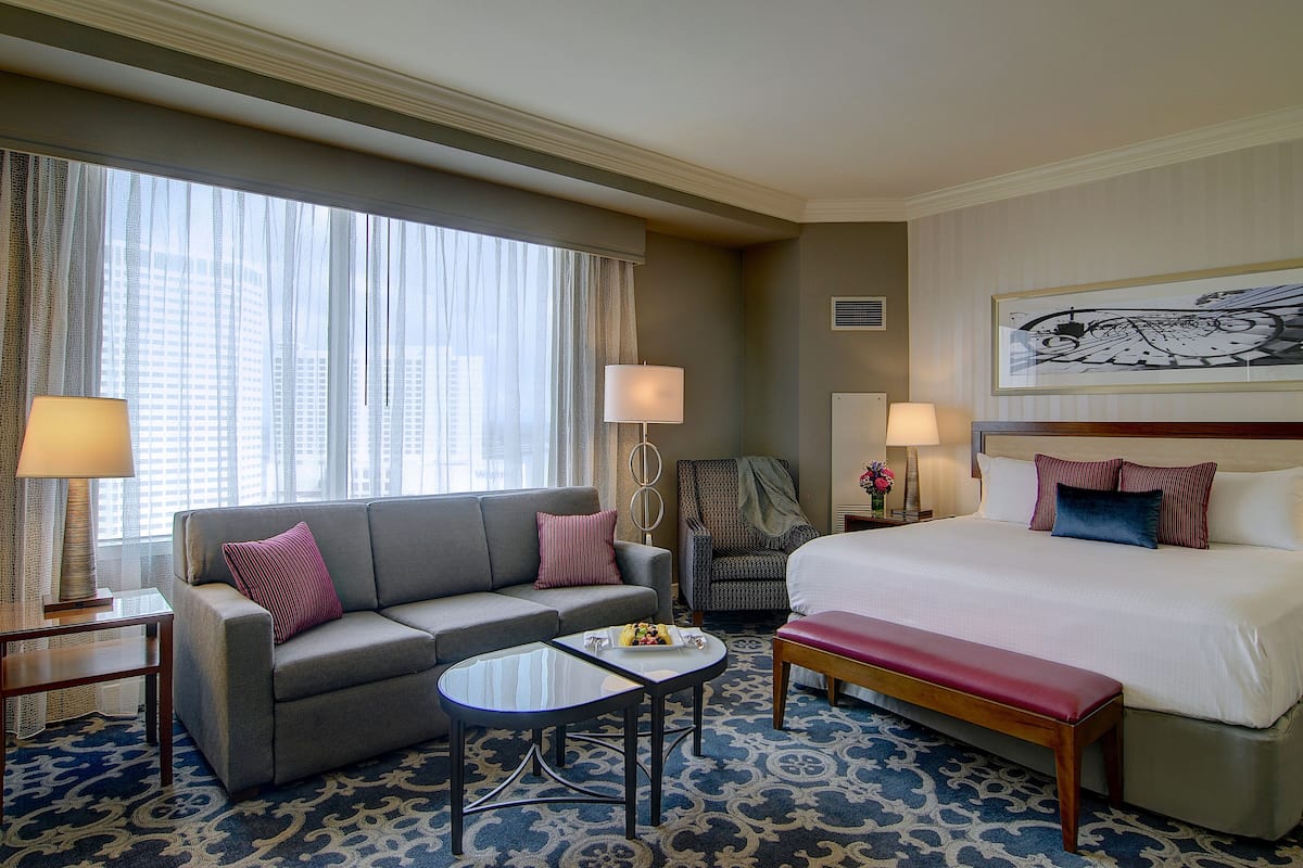Ein Hotelzimmer mit einem Bett, einem Schlafsofa, einem kleinen Tisch und einem Sessel.