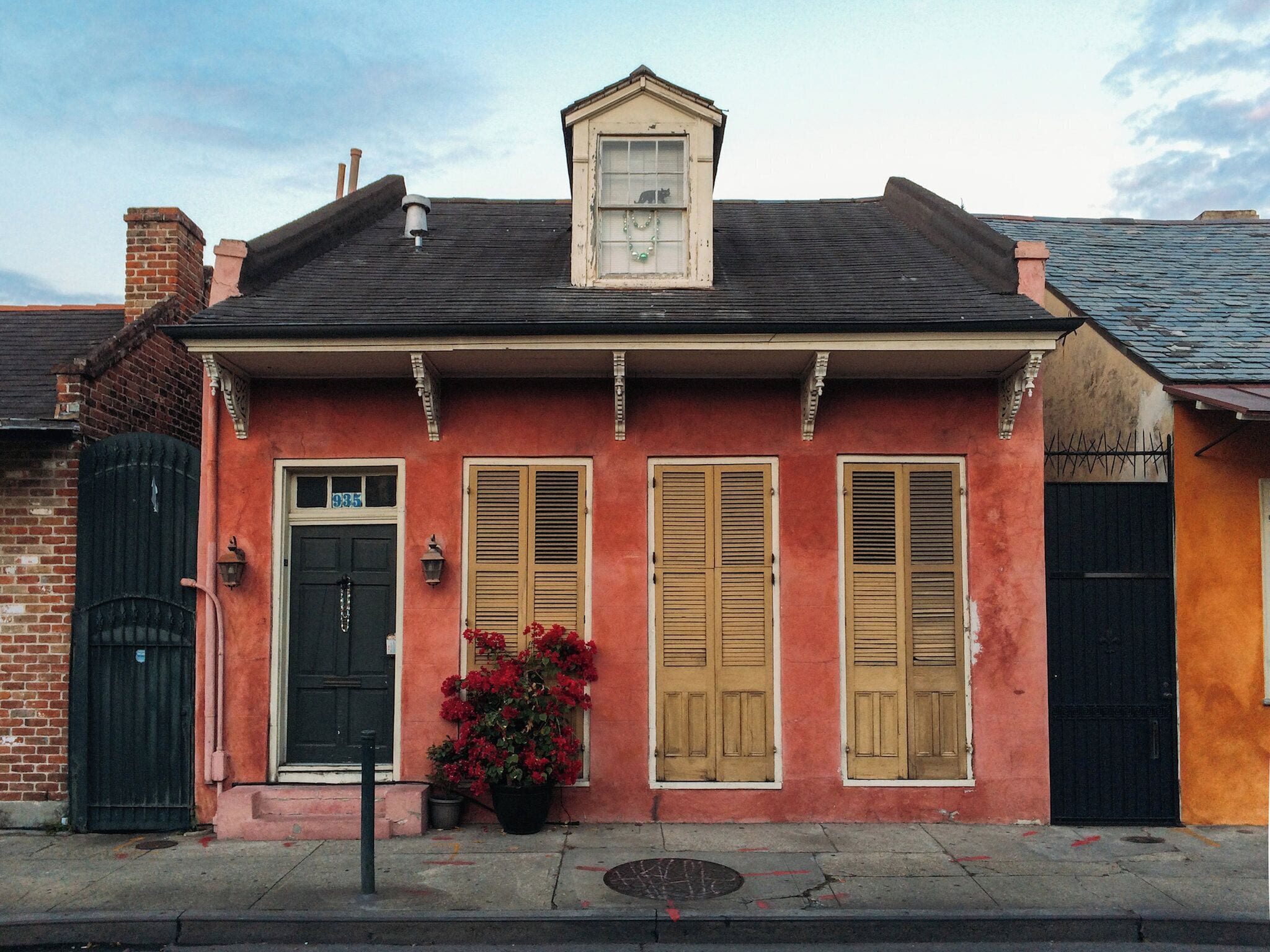 A two-story building with a black door, wooden shutters, and a small dormer window.