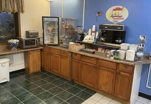 Ein Frühstücksbereich mit Kühlschrank, Kaffeemaschine und verschiedenen Speisen auf der Arbeitsplatte.