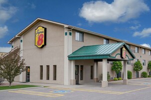 Un hotel Super 8 con fachada color beige, toldo verde y estacionamiento con espacios para discapacitados.