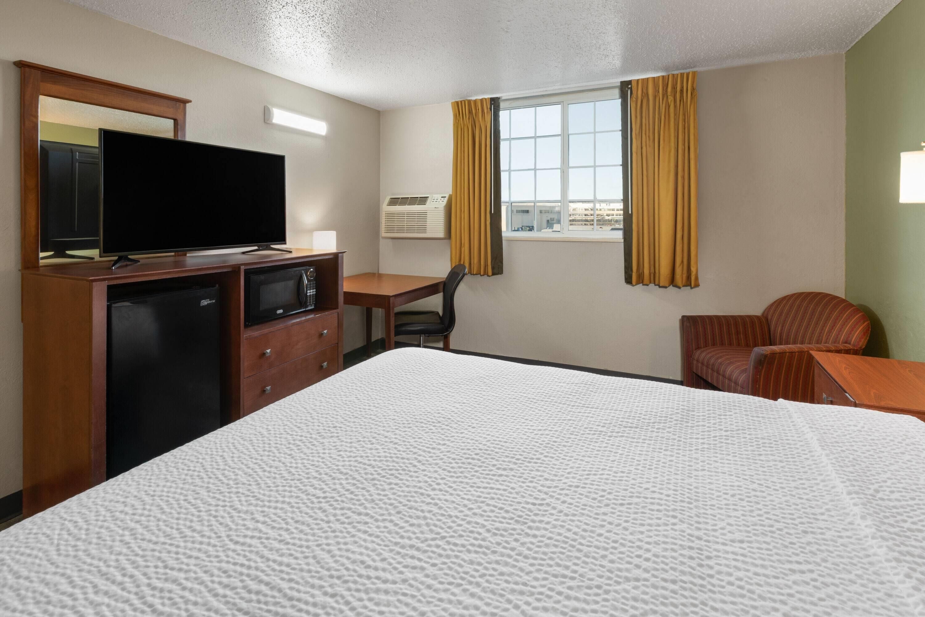 Une chambre d’hôtel équipée d’un lit, d’un bureau, d’une chaise, d’une télévision et d’un appareil de climatisation.