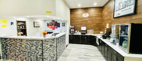 A reception area with a counter, a coffee machine, and a sign indicating an office.