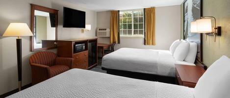 A hotel room with two beds, a desk, a chair, a TV, and a window with curtains.