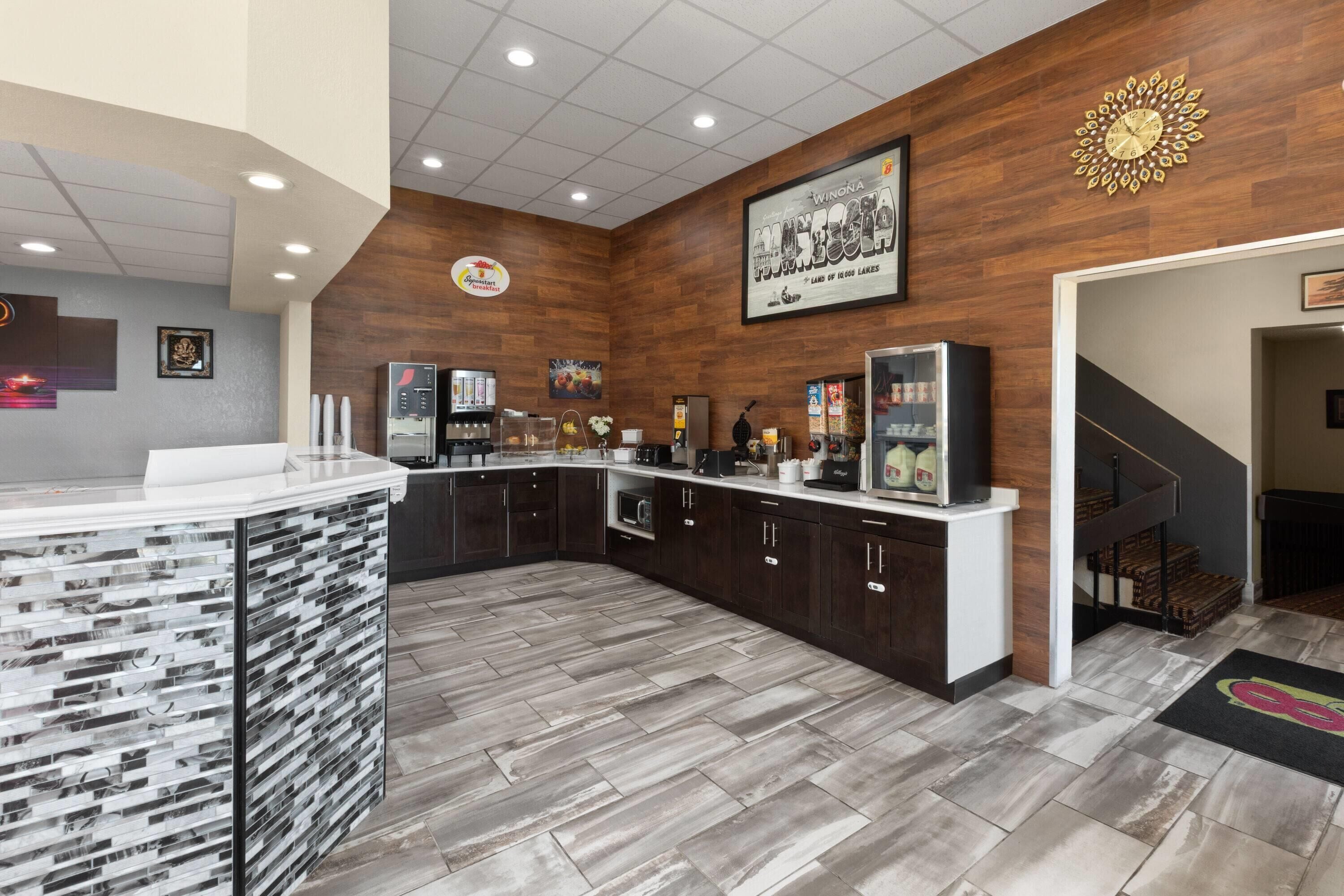 Una cocina moderna con una isla de piedra, armarios de madera oscura y una pared de acento en madera con un reloj.