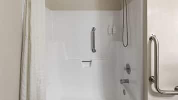 Ducha a nivel con bañera blanca, barras de apoyo y cabezal de ducha manual.