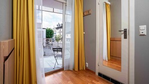A room with a sliding glass door leading to a balcony, a wooden floor, and a door with a mirror. - Thon Hotel Lillestrøm (Lillestrom)
