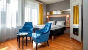 A hotel room with a bed, two blue armchairs, a small table, and a mirror above the bed. - Thon Hotel Lillestrøm (Lillestrom)