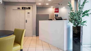 A hotel reception area with a reception desk, a seating area with yellow chairs, an elevator, and a potted plant. - Thon Hotel Lillestrøm (Lillestrom)