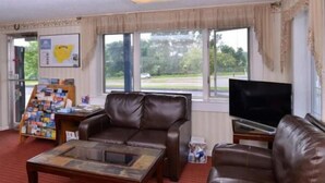 A living room with leather sofas, a coffee table, a television, and a window with a view of the outdoors. - Best Stay Inn - Manchester (Manchester)