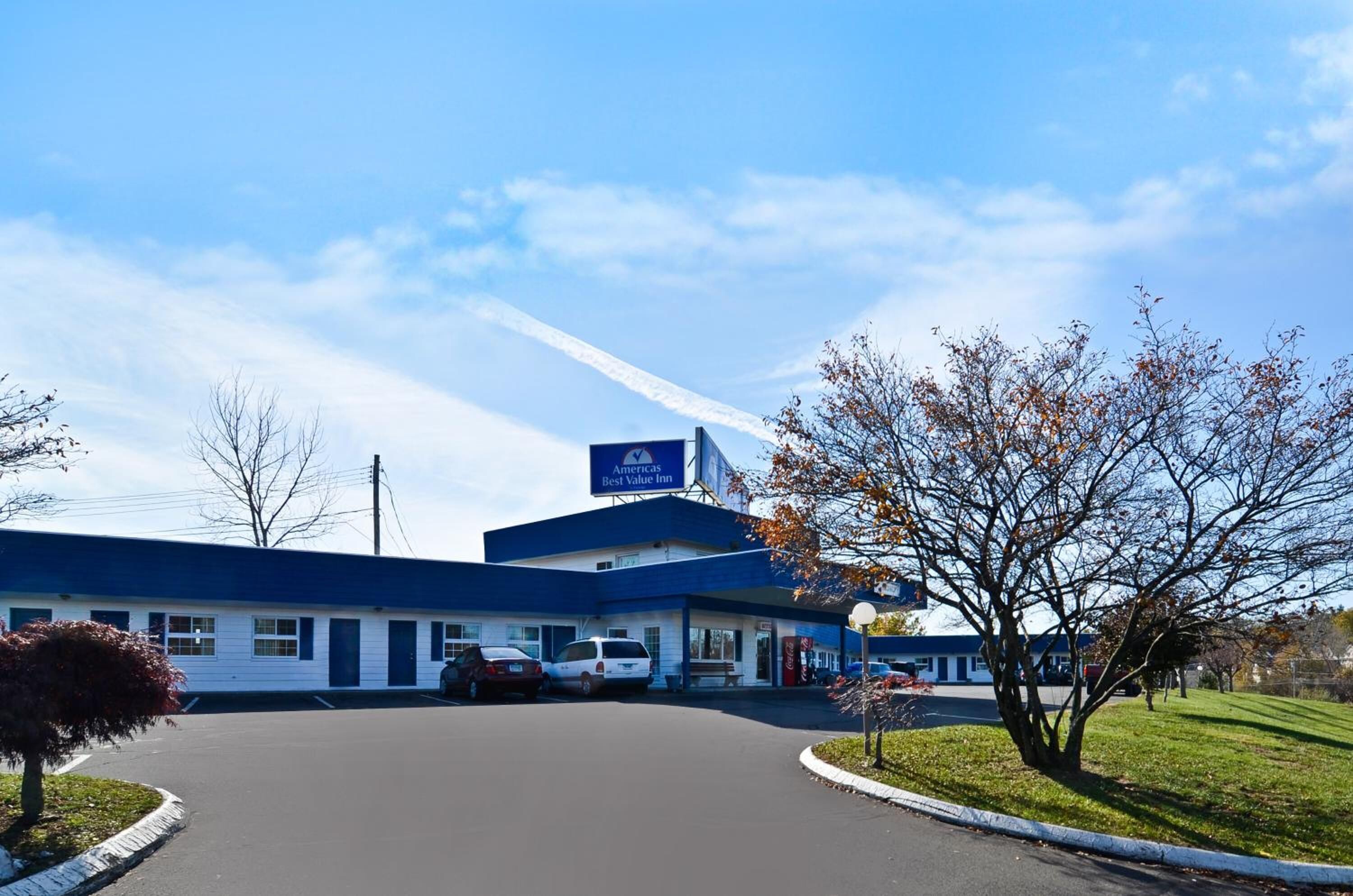 A Best Value Inn with a blue and white exterior, a parking lot, and a clear sky.