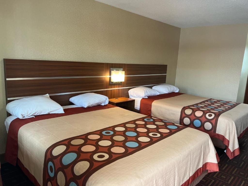 A hotel room with two beds, each with a headboard and a bedside table.