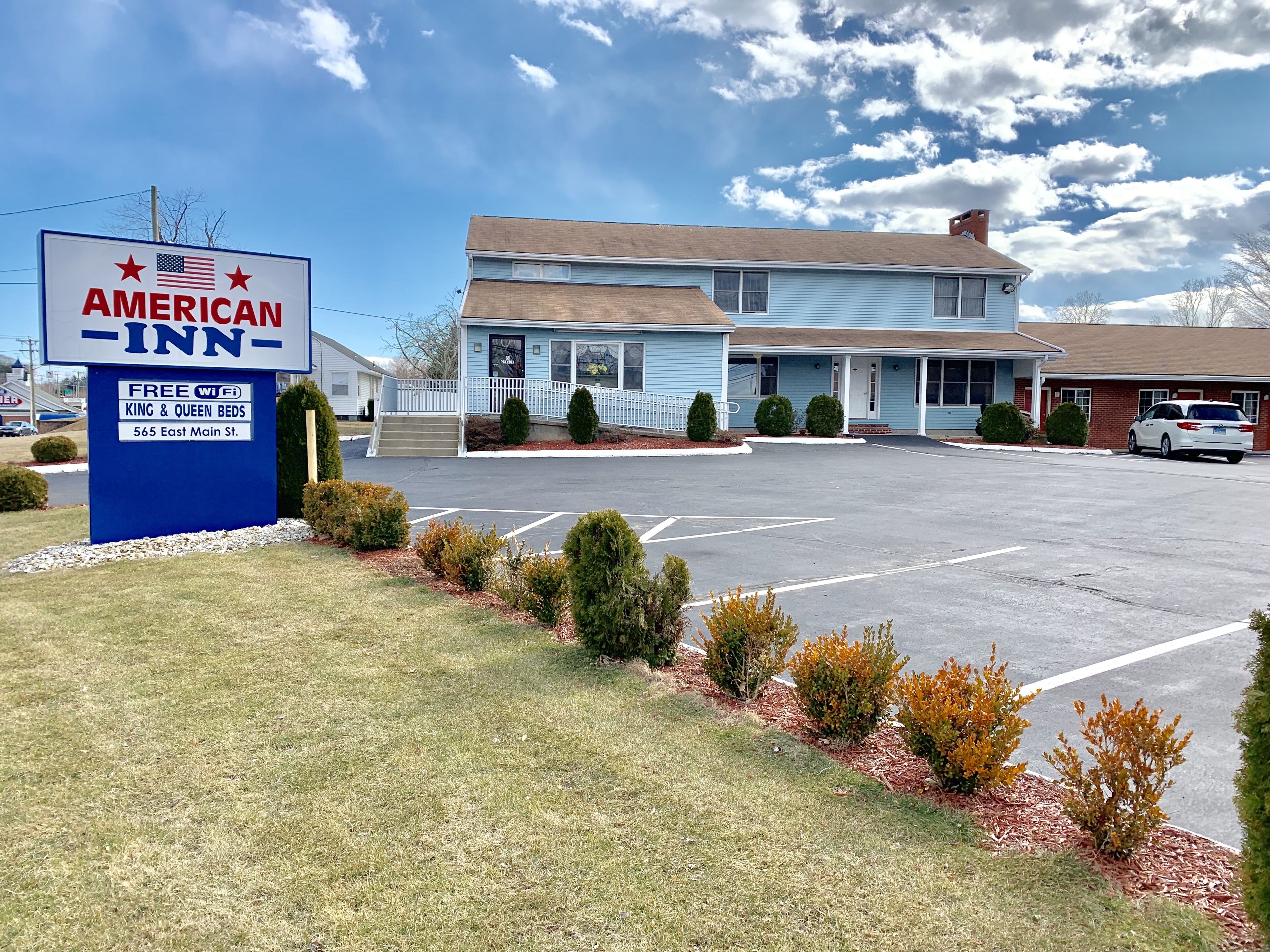 An American Inn with a signboard advertising free WiFi, king & queen beds, and a location at 565 East Main St.