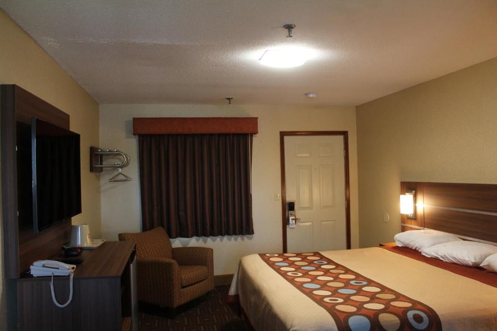 Een hotelkamer met een bed, een bureau, een stoel, een televisie en een deur.