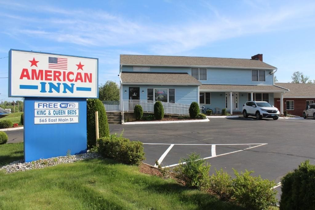 An American Inn sign with a parking lot and a two-story building in the background.