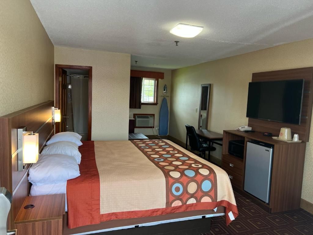Een hotelkamer met een bed, bureau, televisie en een kleine koelkast.