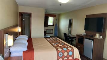 Een hotelkamer met een bed, bureau, televisie en een kleine koelkast.