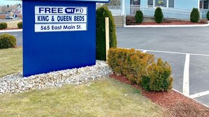 A sign for American Inn with a flag, stars, and a mention of free Wi-Fi and king & queen beds. - American Inn (Branford)