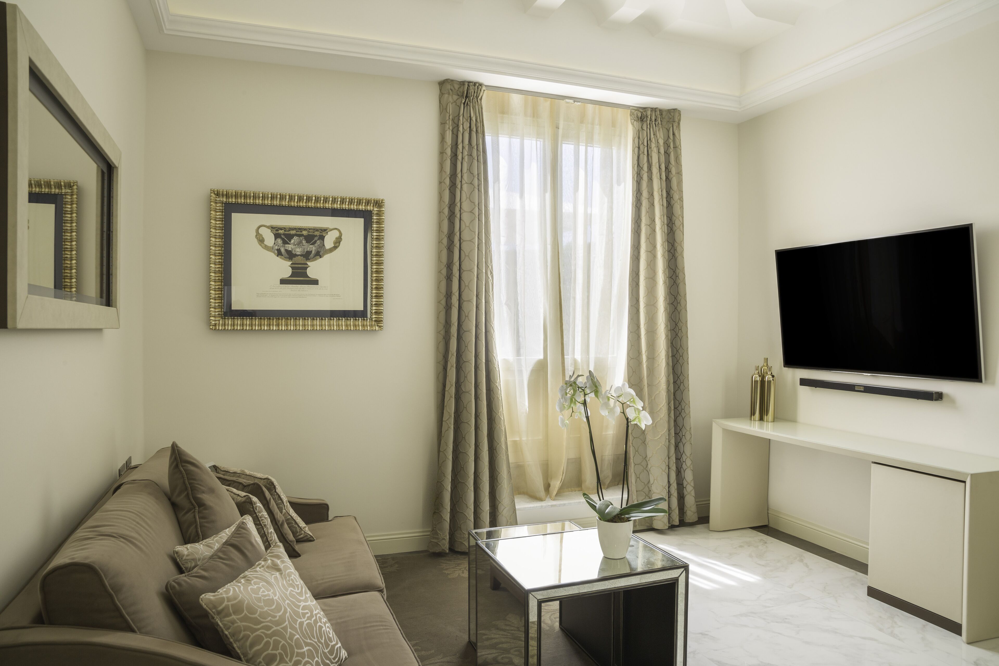 A modern living room with a sofa, a coffee table, a TV, and a window with curtains.
