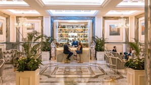 A bar area with a marble floor, bar stools, and a well-stocked shelf. - Aleph Rome Hotel Curio Collection by Hilton (Rome)