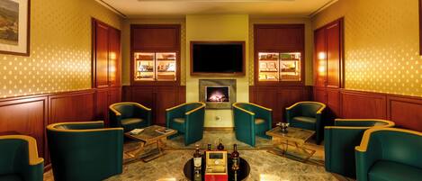 A hotel lobby with a fireplace, wooden cabinets, and teal armchairs.