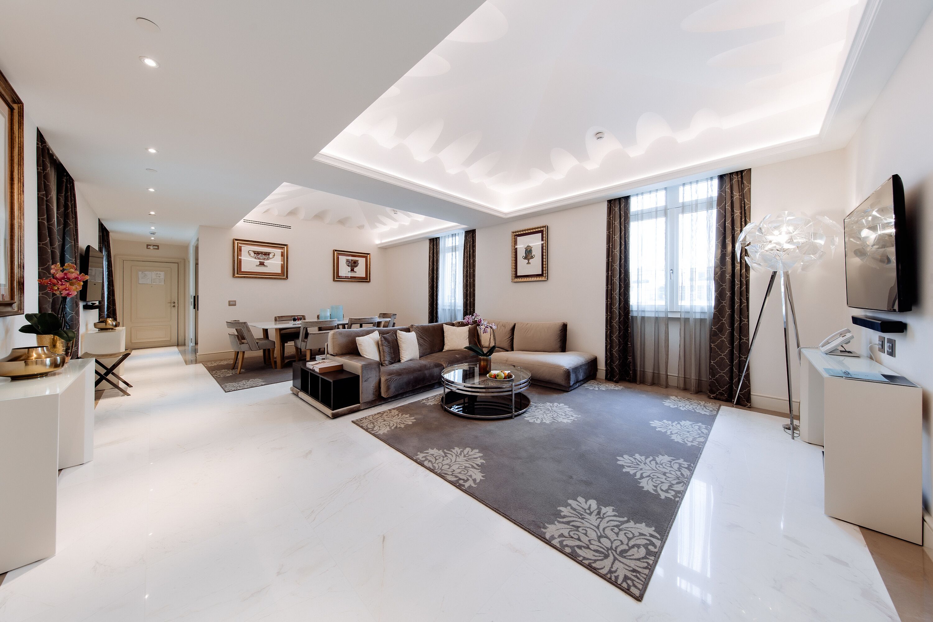 A spacious living room with a modern sofa, a coffee table, and a dining area with a table and chairs.