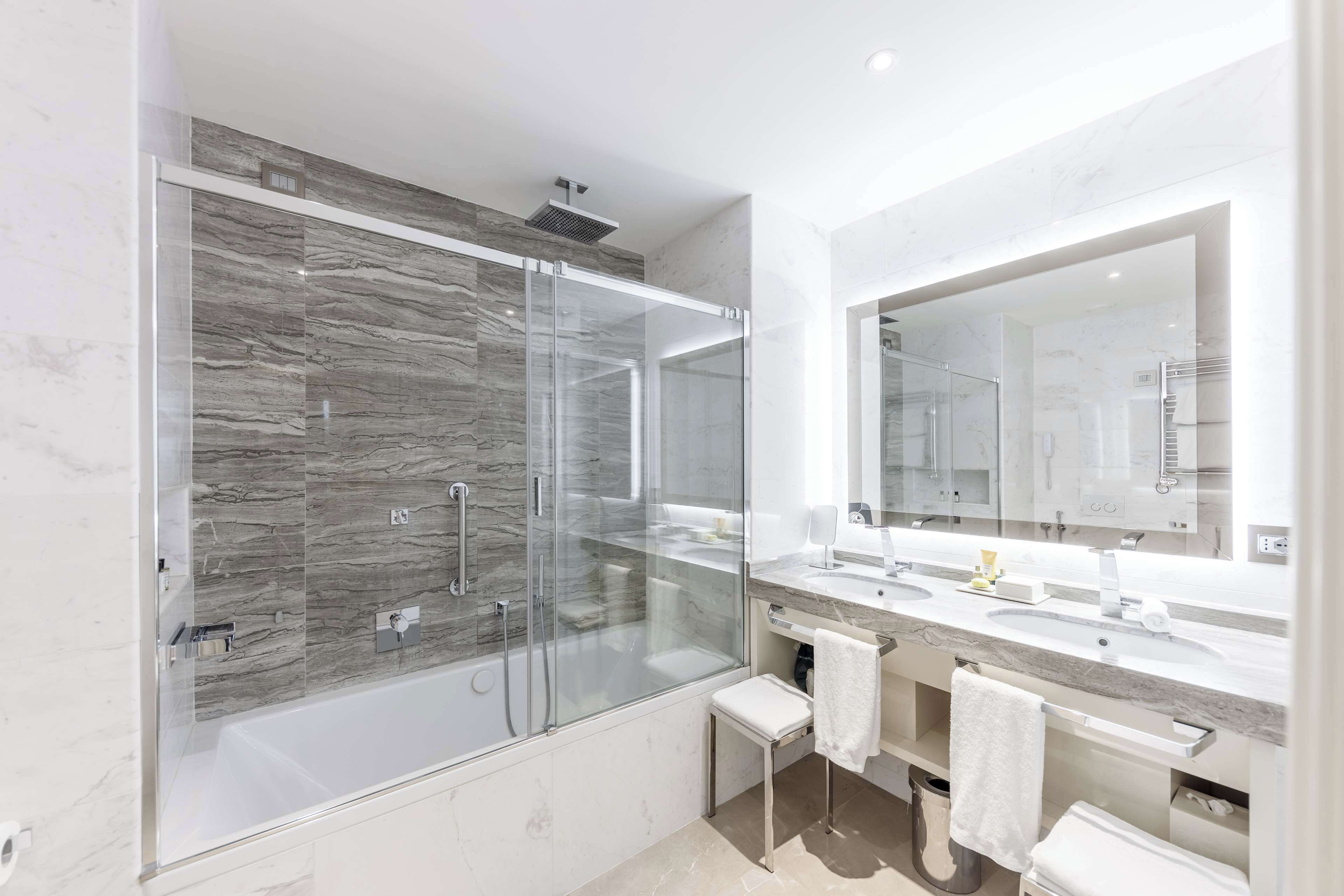 Une salle de bain moderne dotée d’une douche à parois de verre, de deux vasques et d’un grand miroir.
