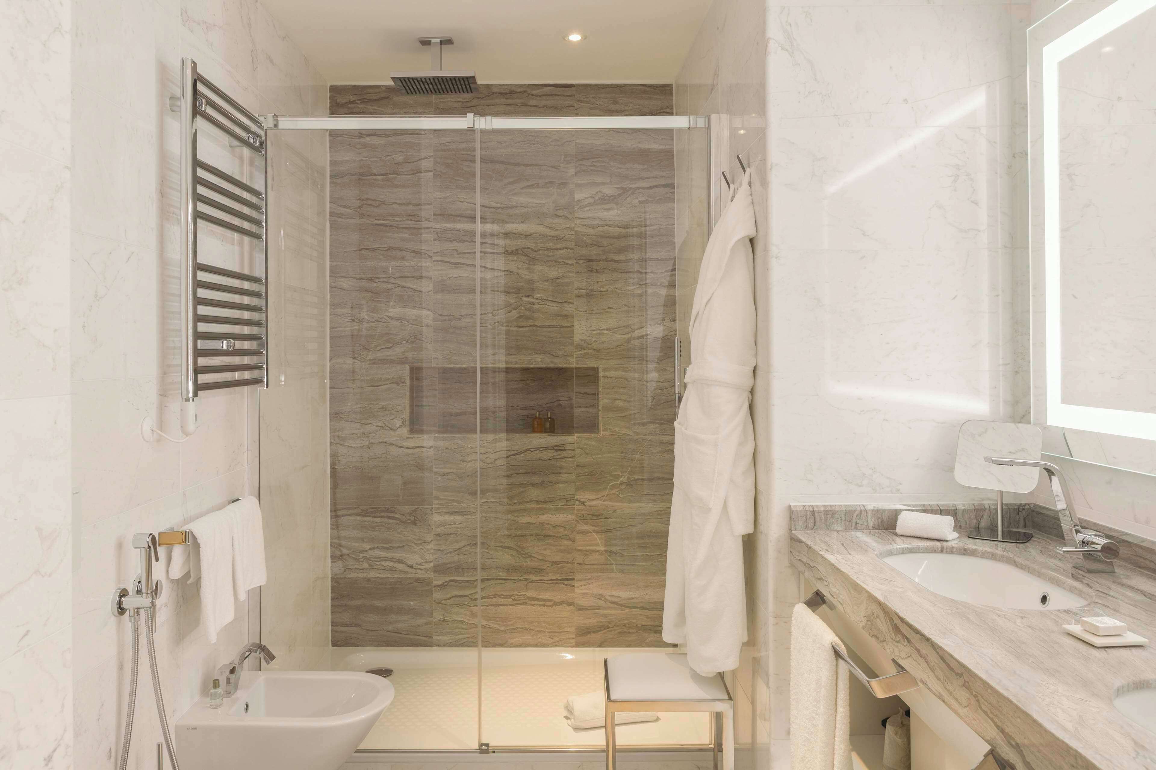Een moderne badkamer met een douchecabine, een wastafelmeubel en een handdoekrek.