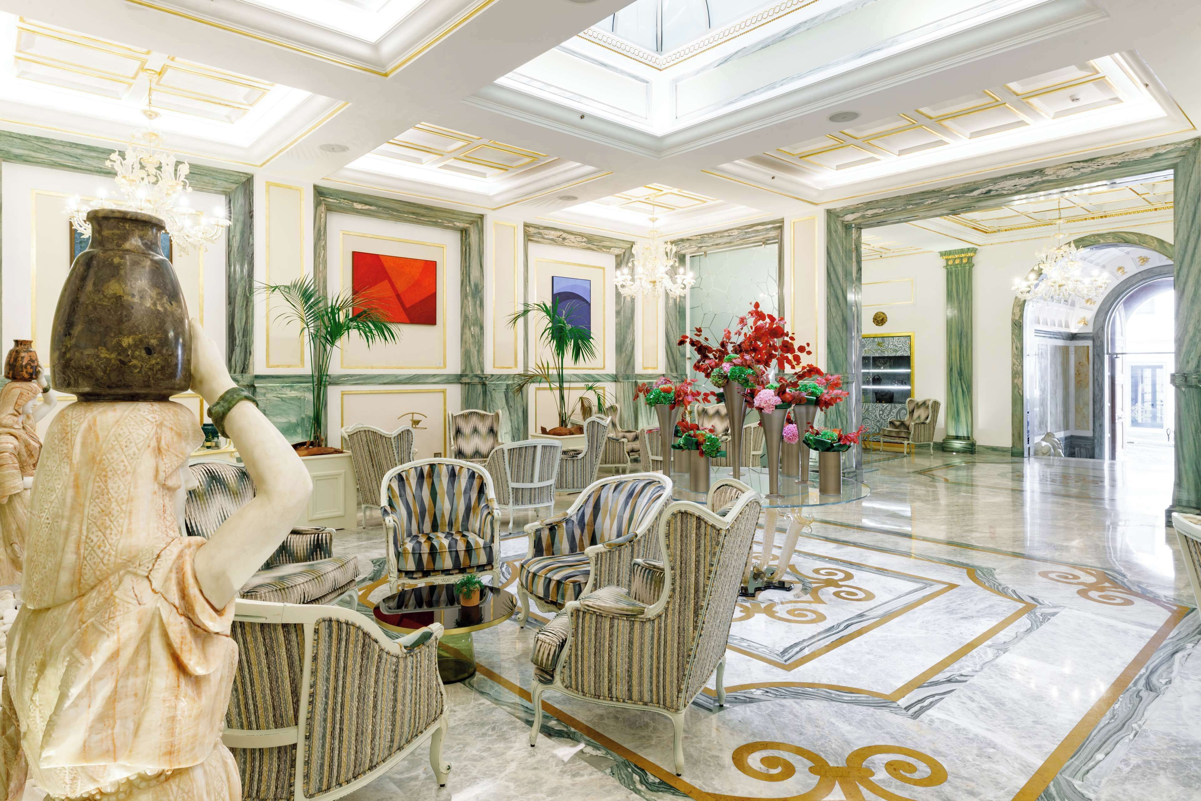 A spacious lobby with a marble floor, classic furniture, and a large vase.