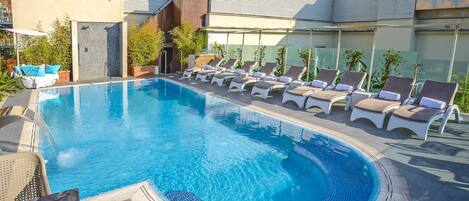 A swimming pool with lounge chairs and a modern building in the background.