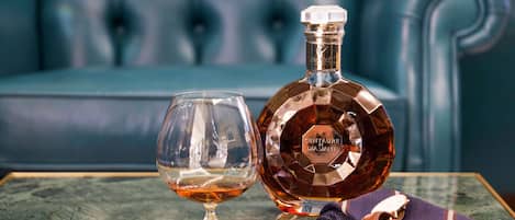 A bottle of Centaurie Diament on a marble table with a glass and two cigars.