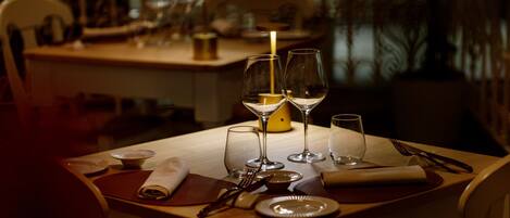 A dining table set with plates, cutlery, and wine glasses, with a candle on the table.