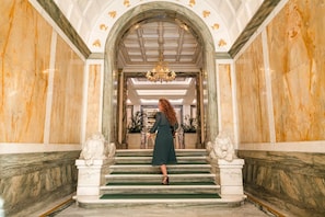 A grand marble staircase with a woman in a dark dress descending. - Aleph Rome Hotel Curio Collection by Hilton (Rome)