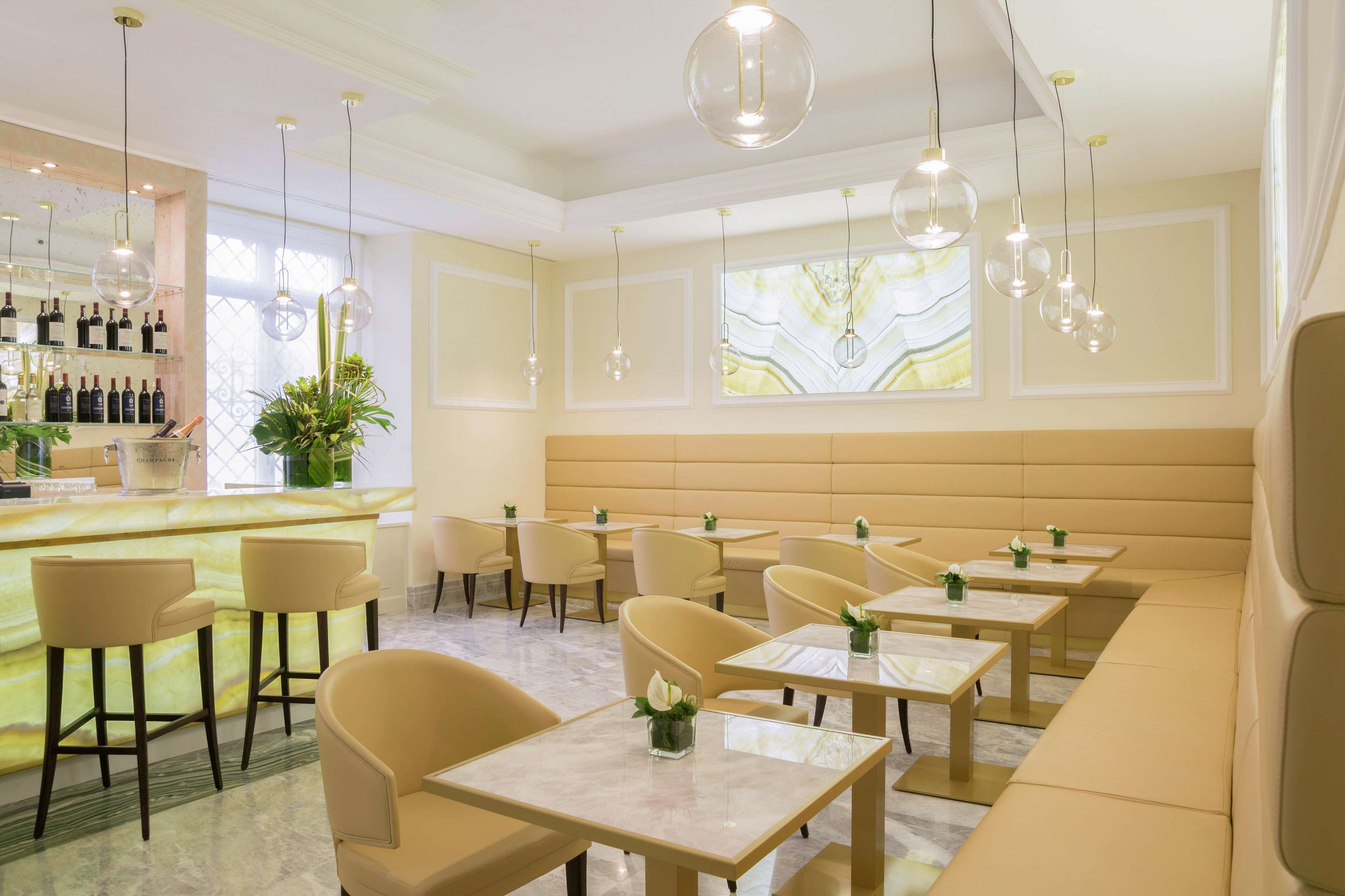 A modern restaurant with a bar area, multiple seating options including booths and tables, and a decorative wall with a large window.
