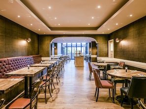 A spacious restaurant with high ceilings, multiple dining areas, and a central bar.