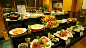 Buffet com diversos pratos, incluindo saladas, frutos do mar e legumes.