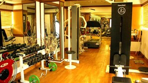 Uma academia com diversos equipamentos de exercícios, incluindo halteres, um banco de musculação e uma máquina Smith.