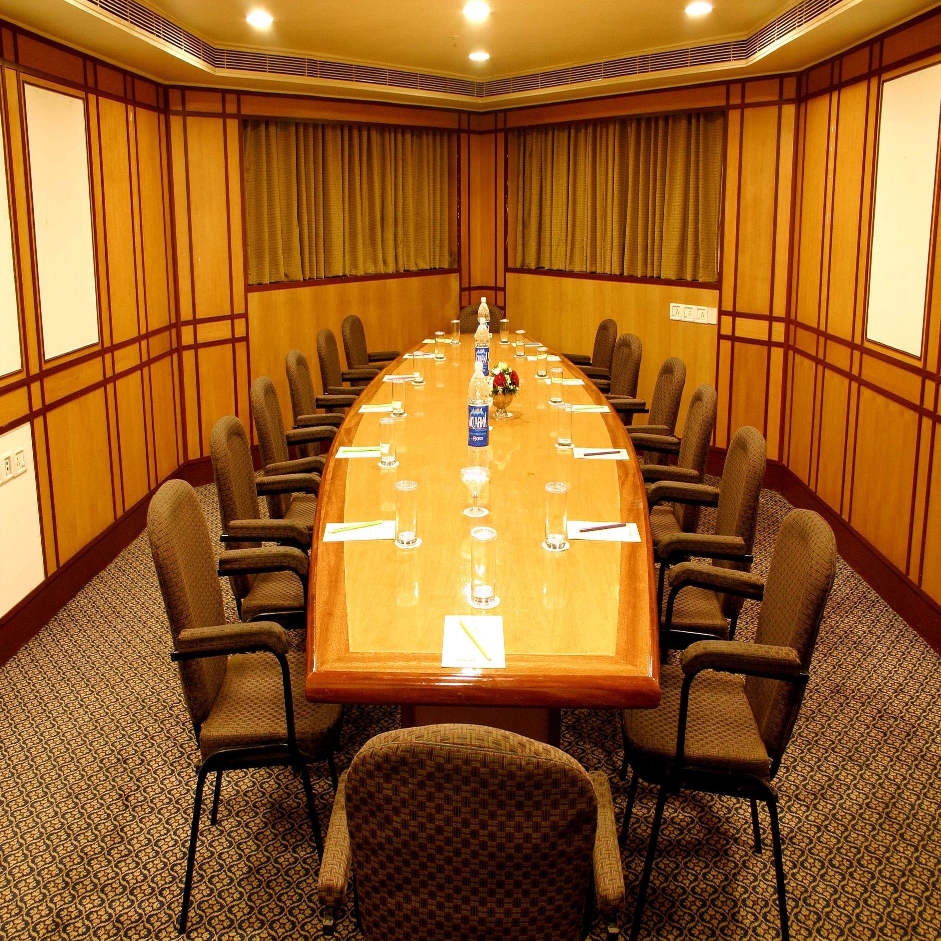 Una sala de conferencias con una mesa larga, sillas y piso alfombrado.