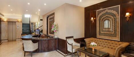 A spacious lobby with a reception desk, seating area, and a staircase leading to an upper floor.