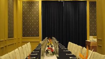 Un salón de conferencias con una larga mesa dispuesta para una reunión, flanqueado por filas de sillas.