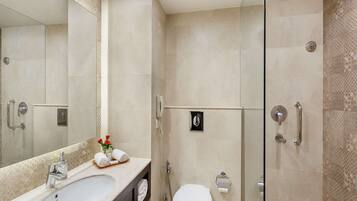 Un baño moderno con un espejo grande, un lavabo, un inodoro y una zona de ducha.