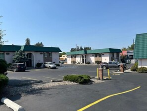 A parking lot with several cars and a building with a green roof.