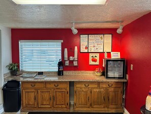 A kitchen with wooden cabinets, a refrigerator, a coffee machine, and a sign offering free takeout.