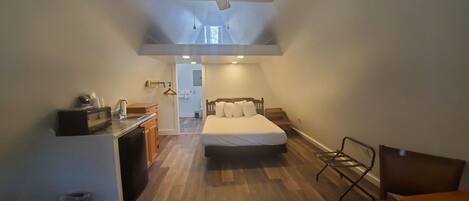 A compact room with a bed, a desk, a chair, and a ceiling fan.