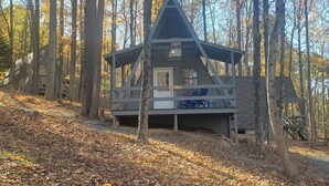 A cabin with a triangular roof, a porch with chairs, and a sign reading "EGRET 57". - Coolfont Resort (Berkeley Springs)