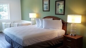 A bedroom with a large bed, two bedside tables with lamps, a desk, and two framed pictures on the wall. - Coolfont Resort (Berkeley Springs)