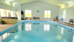 An indoor swimming pool with clear blue water, surrounded by chairs and potted plants. - Coolfont Resort (Berkeley Springs)