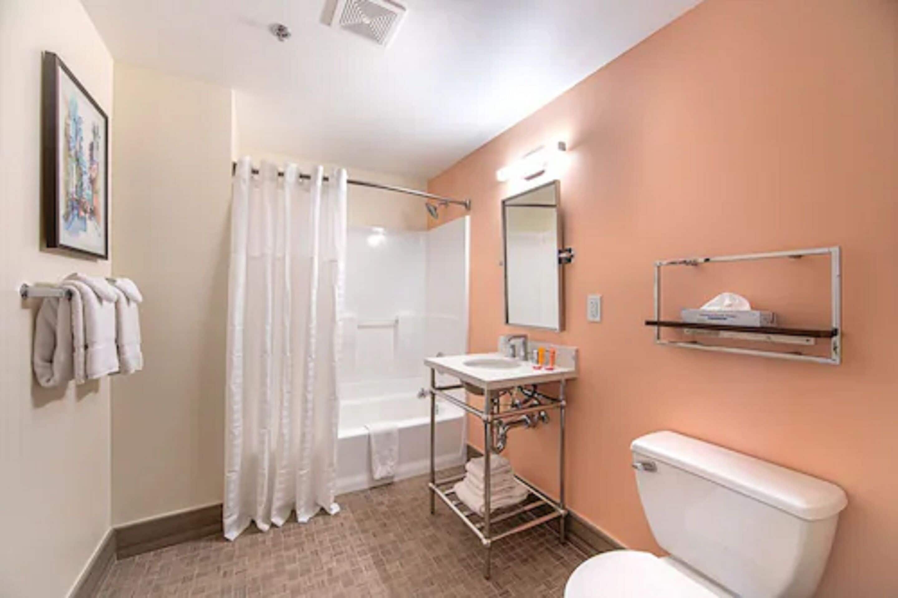 A bathroom with a shower, toilet, sink, and towel rack.