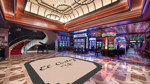 A lobby with a grand staircase, a bar area, and multiple gaming machines. - El Cortez Hotel and Casino - 21 and Over (Las Vegas)