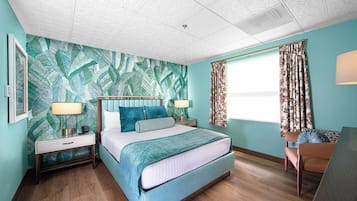 A bedroom with a bed, nightstands, a desk, and a window with curtains.